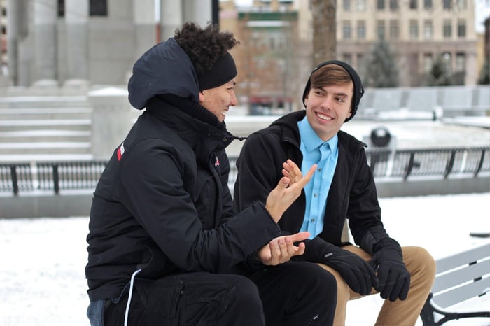 Adult talking to teenage bully outside on bleachers