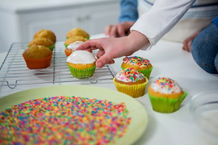 Boy placing cupcake on tray in the kitchen