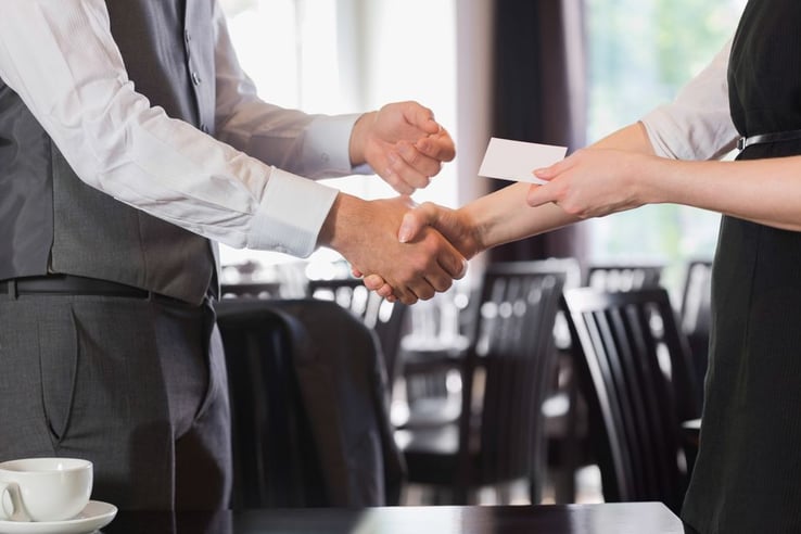Business people shaking hands after meeting and changing cards in restaurant