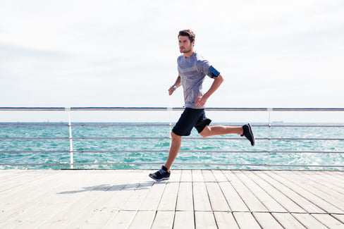 Full length portrait of a sports man running outdoors near sea