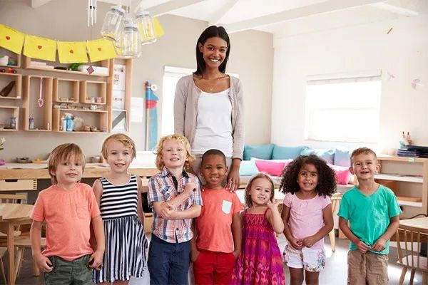 Daycare teacher with a diverse group of young children, symbolizing child care enrollment.