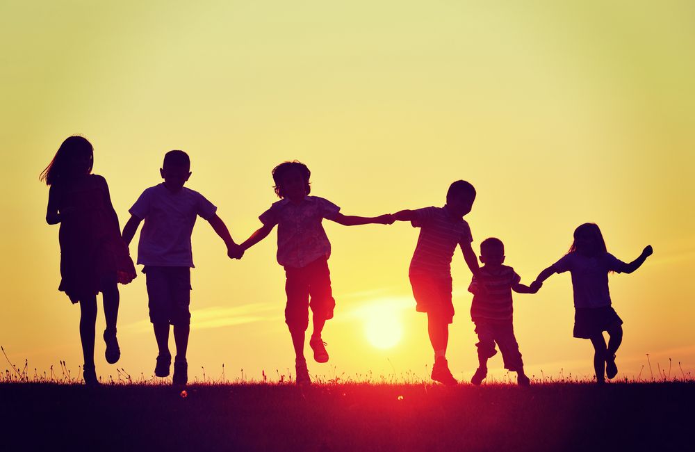 Happy children's ministry group running during a sunset