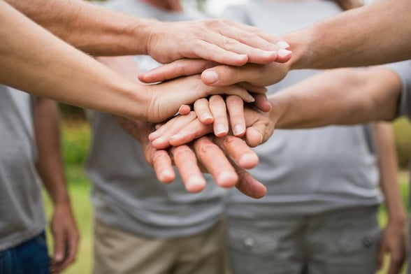 Group of volunteers putting hands together during a community-based fundraiser