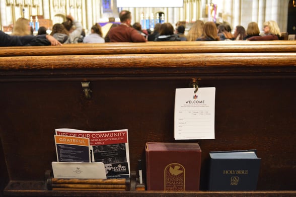 Image showing a perspective of sitting in a church pew, with a Bible and notebook in front
