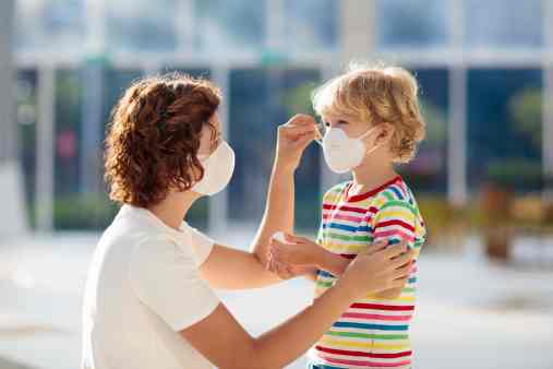 woman helping a preschooler with a face mask