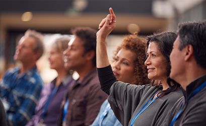 woman-raising-hand-in-group-of-adults