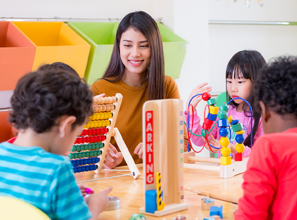 teacher-and-children-playing-with-toys-at-table