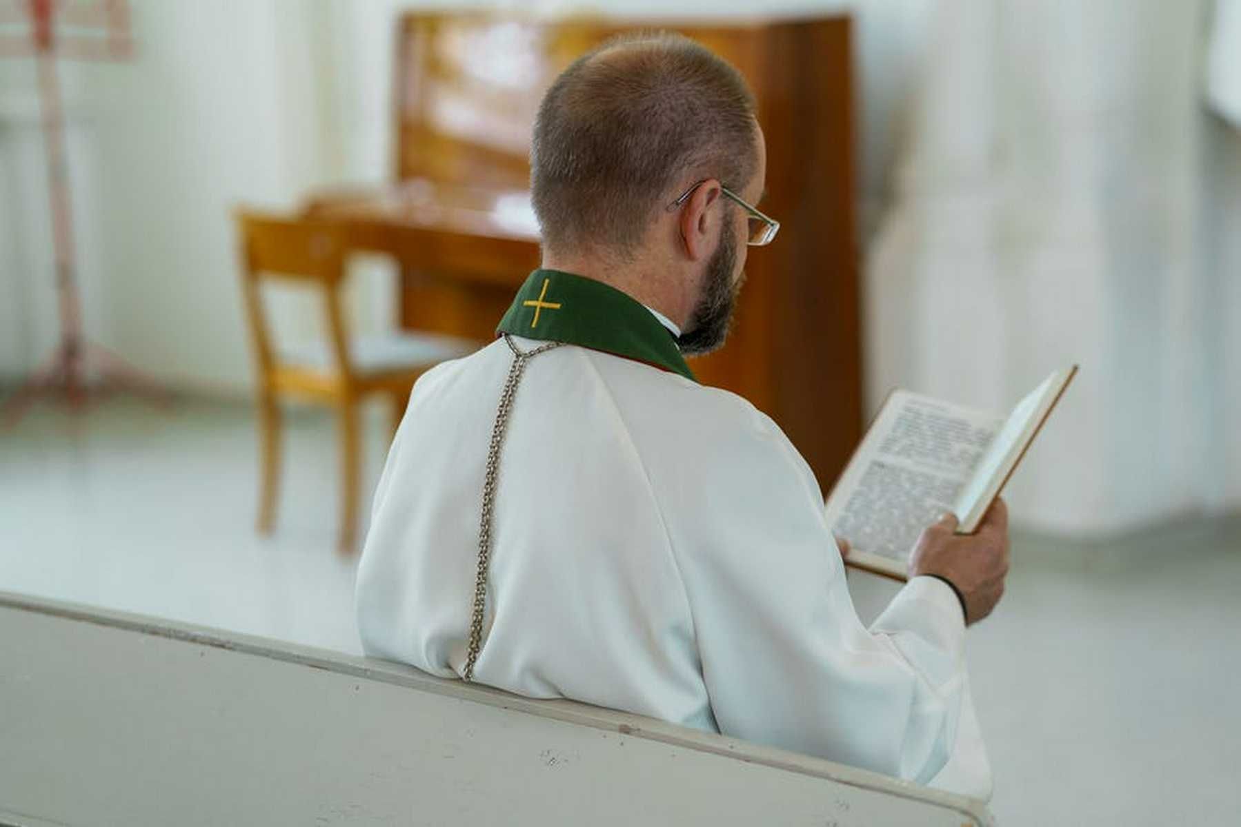 Pastor Reviewing Bible Passage in Pew for Church Welcome
