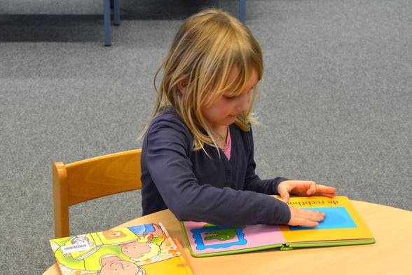 Preschooler reading book during reading class activity