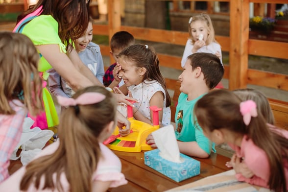 Preschool teacher demonstrating simple adaptable activities with colorful manipulatives in small groups