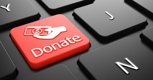Donate with Money in the Hand Icon - Red Button on Black Computer Keyboard.