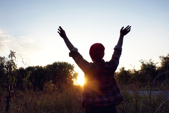 Thanksgiving image of a person showing gratitude, with their hands up in the air towards the sky