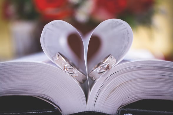 Wedding rings in a Bible, with the pages forming a heart