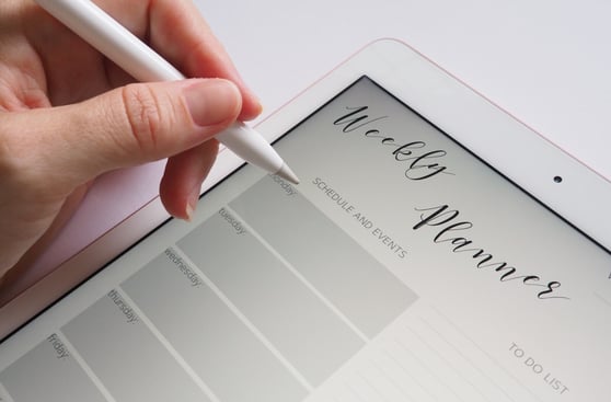 Woman Filling Out a Weekly Event Planner on Tablet