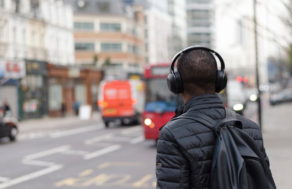 Young man walking on street listening to his churchs podcast