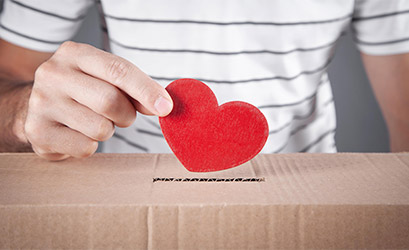 Photo of someone putting a heart in a box, representing a love offering