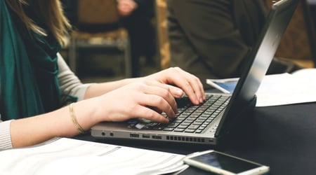 Image of woman typing up an event email on her laptop