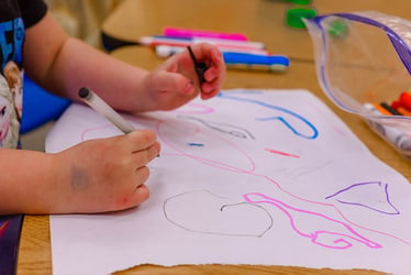 Preschool student drawing with markers