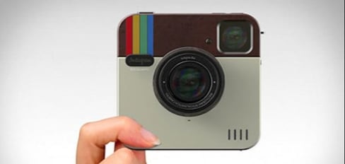 Person Holding Camera In Shape of Instagram Symbol