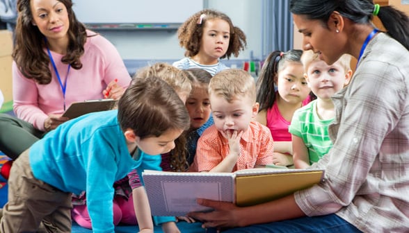 Students and teacher reviewing their childcare parent handbook